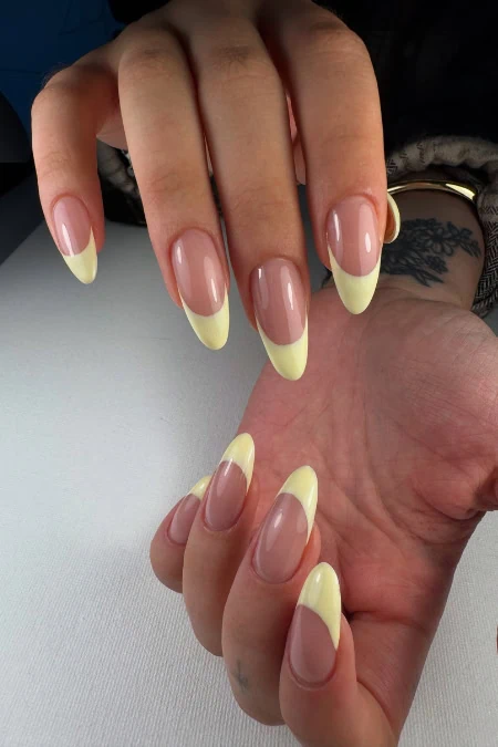 Woman's hands with soft butter yellow French tip Summer nails.