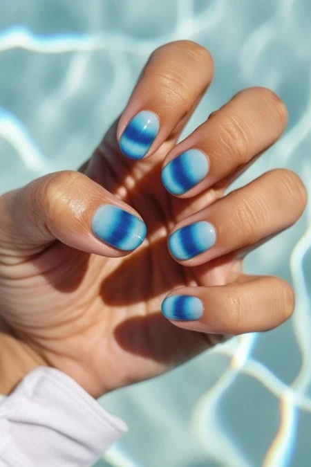 Beautiful hand with blue ombre nail polish design, showcasing trendy and vibrant nail art perfect for summer or special occasions.