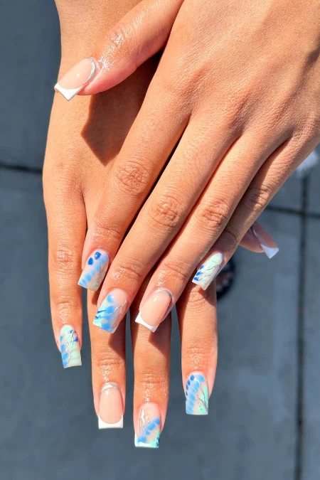Elegant blue and white nail art with floral and abstract patterns, perfect for a stylish and modern look. Showcasing well-manicured hands with creative square nails designs for beauty and self-care.