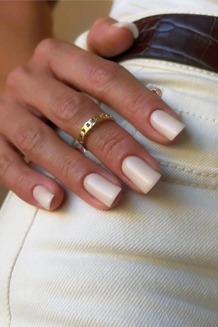 woman's hand with a gold ring and well-groomed nails, showcasing fashionable jewelry and personal style.