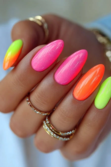 Vibrant neon pink, orange, and green nail art on well-manicured fingers, showcasing trendy and eye-catching summer nail designs. Perfect for beauty, fashion, and nail art enthusiasts.