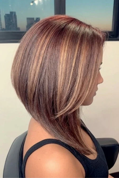 A woman with a sleek, straight chestnut brown bob hairstyle, showcasing shiny, healthy hair with subtle highlights, styled to frame her face elegantly.