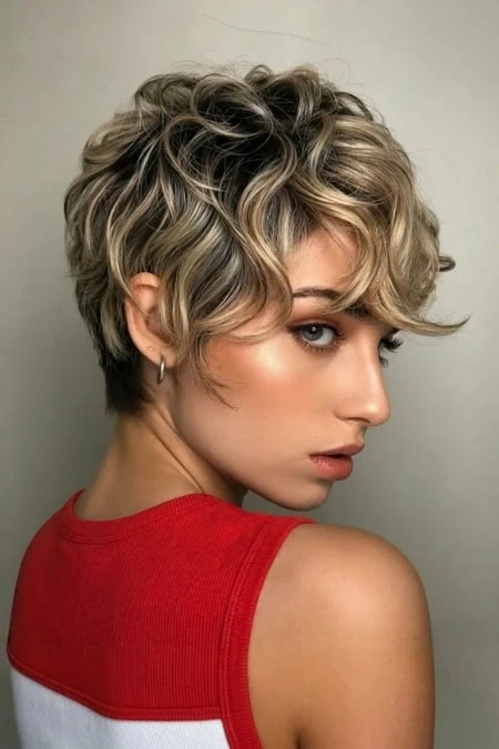 A stylish short curly blonde bob hairstyle featuring voluminous, textured curls with a side part, perfect for a modern, edgy look.