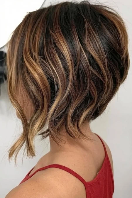 Elegant short layered bob with caramel highlights, soft waves, and a trendy, chic appearance for a fashionable hairstyle.