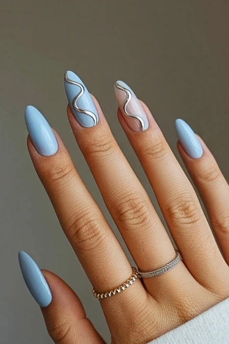 Stylish blue and white nails with silver on well-manicured fingers, highlighting trendy and creative nail design for beauty and self-care.