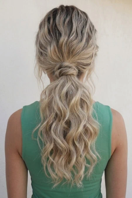 Beautiful blonde wavy hairstyle that is a loose ponytail, showcasing healthy, shiny, and voluminous hair with natural waves. Perfect for a casual or elegant look, emphasizing hair care and styling tips.