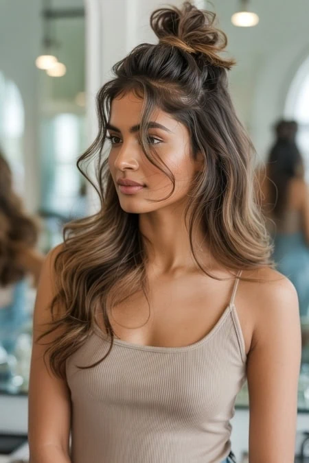 Young woman with long, wavy hair styled in a casual top knot, showcasing effortless beauty and modern hair trends. Perfect for beauty, haircare, and lifestyle content.