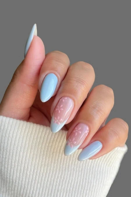 Elegant light blue and pink almond-shaped manicure featuring floral nail art, perfect for spring and summer beauty looks. The image showcases well-groomed nails with a soft, feminine design.
