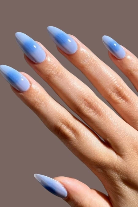 Elegant light blue aura acrylic nails featuring a smooth gradient from light to dark blue, with a shiny, high-gloss finish. Perfect for a stylish, modern manicure look.