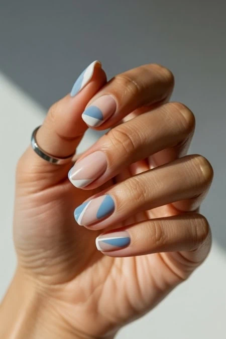 Beautiful hand showcasing modern blue and white geometric nail art with a minimalist style, perfect for beauty and fashion enthusiasts.