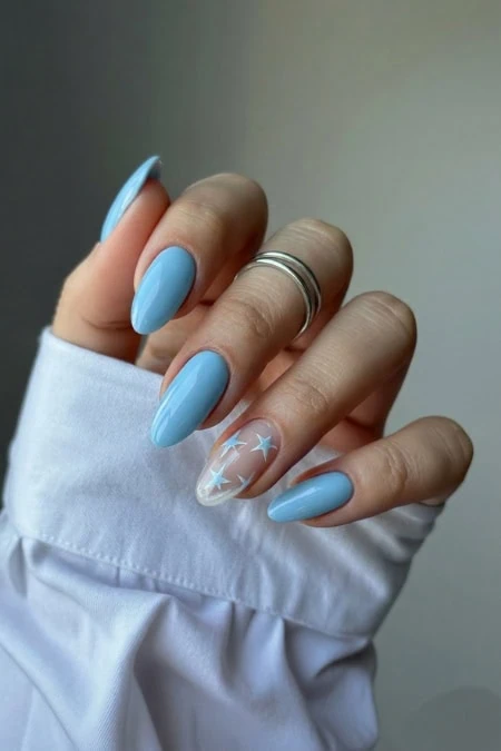 Blue manicure with star design on accent nail, featuring well-manicured nails, stylish nail art, and a focus on beauty, self-care, and personal grooming.