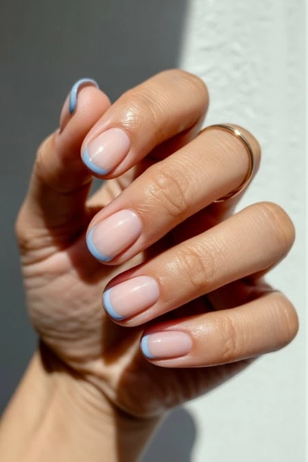 Elegant French manicure with light blue tips on well-groomed nails, showcasing a clean and stylish nail design perfect for beauty and self-care enthusiasts.