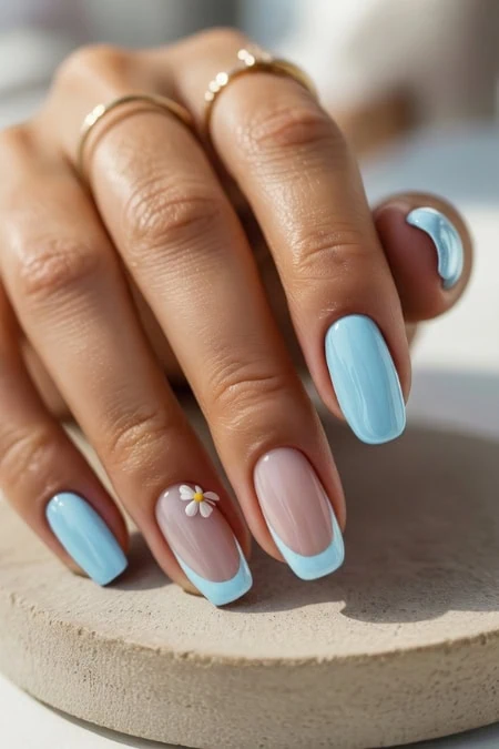 Close-up of a woman's hand with light blue manicured nails, finger touching lips, emphasizing trendy nail art and beauty care for a fresh, stylish appearance.