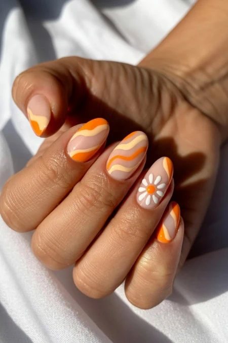 Bright orange and white marbled nail art with a daisy accent on the ring finger, showcasing trendy, vibrant, and stylish manicure design perfect for spring and summer fashion.