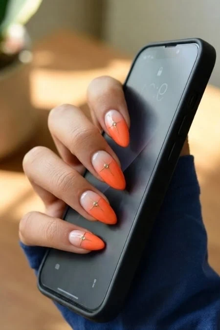 A woman holding a smartphone with orange and white manicured nails, showcasing a beauty and self-care theme.