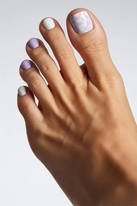 Pastel toenail polish with purple and white checkered design, perfect for summer or spring nail art, showcasing trendy and colorful pedicure ideas.