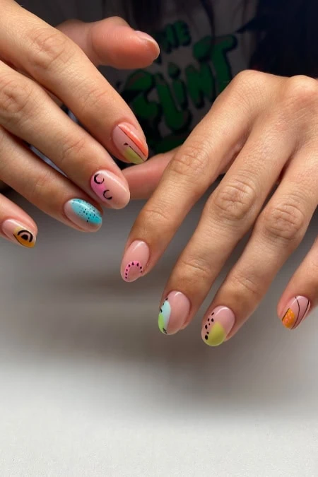 Colorful, artistic nail designs with various patterns and pastel shades on well-manicured fingers, showcasing creative nail art for beauty and fashion.