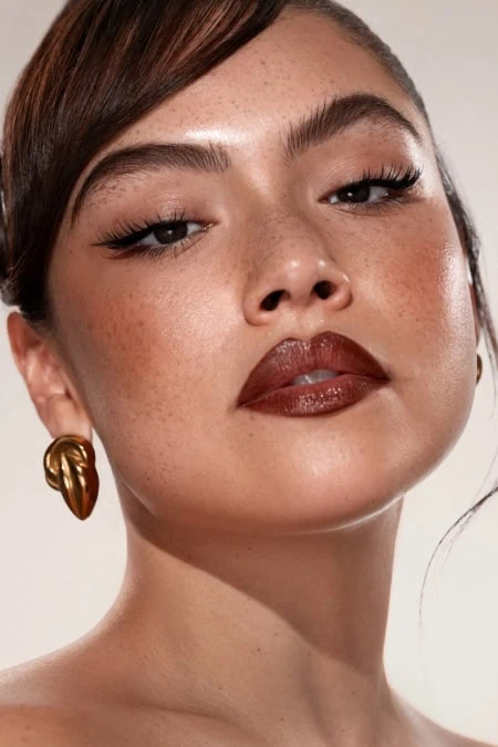 Close-up of a woman with flawless skin, bold fall makeup, and gold earrings, showcasing beauty and skincare focus for The Beauty Deep Life.