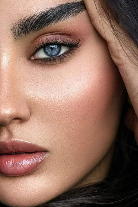 Close-up of a woman's face highlighting her blue eye, well-groomed eyebrows, and flawless skin, emphasizing beauty and fall makeup looks.