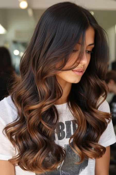 Beautiful long brunette hair with caramel highlights styled in loose waves, showcasing healthy, shiny hair perfect for a beauty and hair care website.