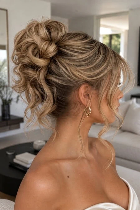 Elegant updo hairstyle with voluminous curls and intricate bun for a formal event or homecoming.