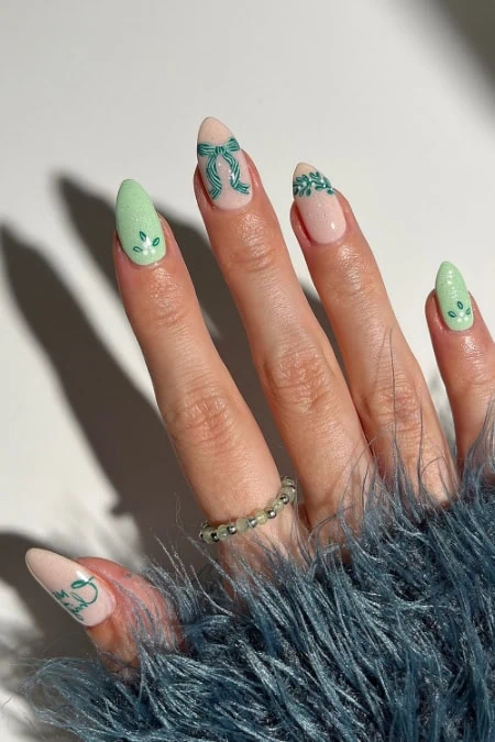 Cute Easter-themed nail art with pastel green, pink, and blue colors featuring bunny, bow, and floral designs on manicured nails.