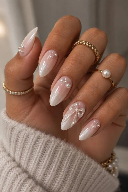 Elegant white almond-shaped nails with pearl and rhinestone accents, showcasing intricate nail art and manicures.