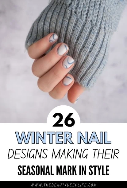 Close-up of a hand with winter nail art featuring blue and gray swirl designs, wearing a cozy gray knitted sweater sleeve.