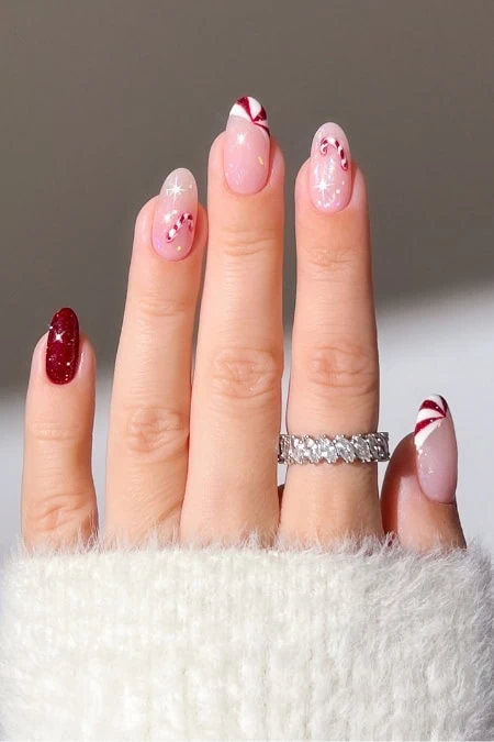 Elegant manicure with pink, red, and white holiday-themed nail art featuring candy cane and snowflake designs, perfect for festive occasions.