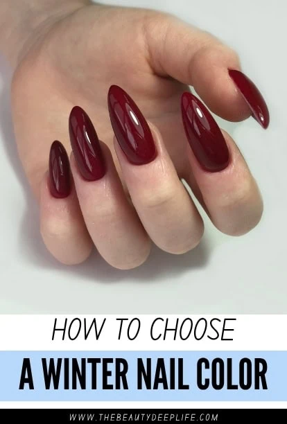 Close-up of a hand with long, almond-shaped nails painted in a deep red winter nail color, showcasing elegant and glossy nail art for winter fashion.