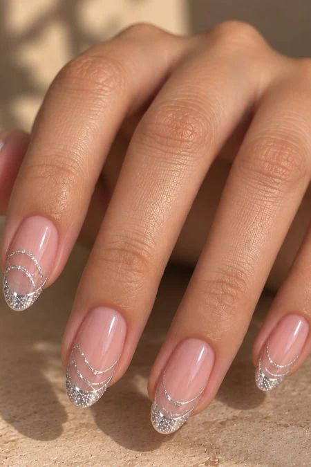 Elegant manicure with clear base and silver glitter French tips on well-groomed nails, perfect for beauty and nail art enthusiasts.