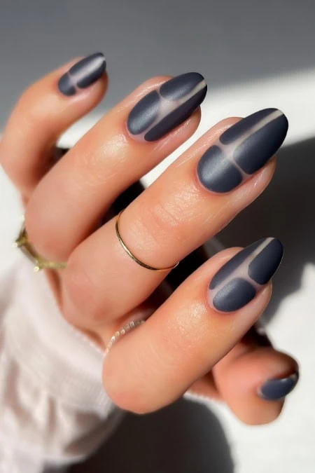 Close-up of stylish matte gray gradient winter nails trend with geometric half-moon design on almond-shaped tips, showcasing modern manicure from The Beauty Deep Life.