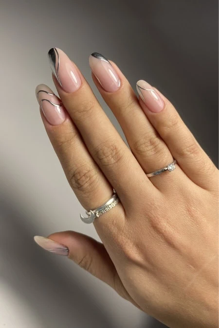Elegant manicure featuring nude pink winter nails trend, complemented by a delicate silver ring on the ring finger and subtle sparkle on the index finger.
